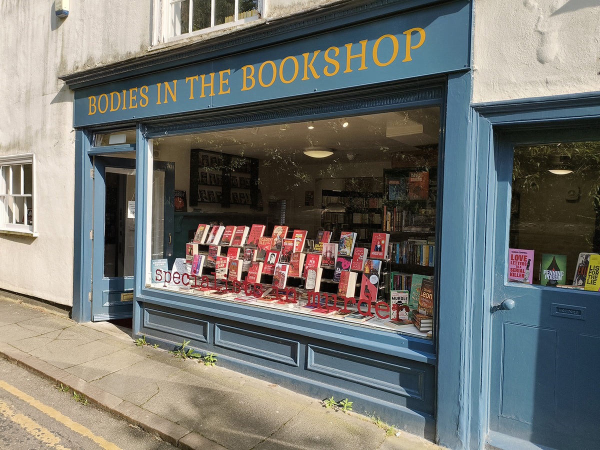 Dark blue Bodies in the Bookshop window full of crime fiction paperbacks